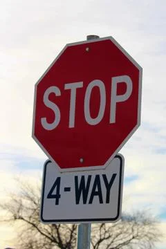 Four Way Stop Sign Against Cloudy Sky Stock Photos