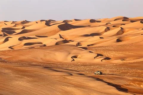 A Four wheel drive car moves across an Arabian desert with beautiful sand dun Stock Photos