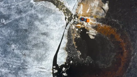 A four-wheel drive SUV breaks the ice and climbs out of the water onto an ice Stock Footage 262790594