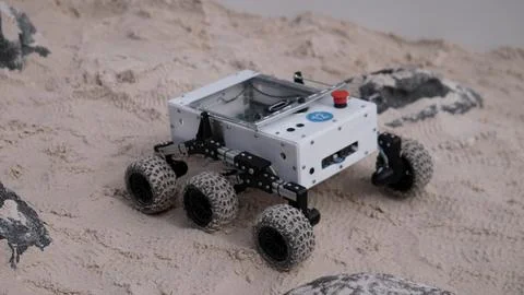 Four wheeled exploration robot navigating sandy terrain with rugged tires Stock Photos