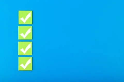 Four white checkmarks on green tablets in a row against blue background with Stock Photos