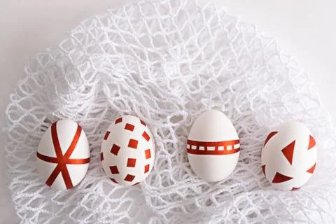 Four white Easter eggs in row decorated with red geometric stripes on white m Stock Photos