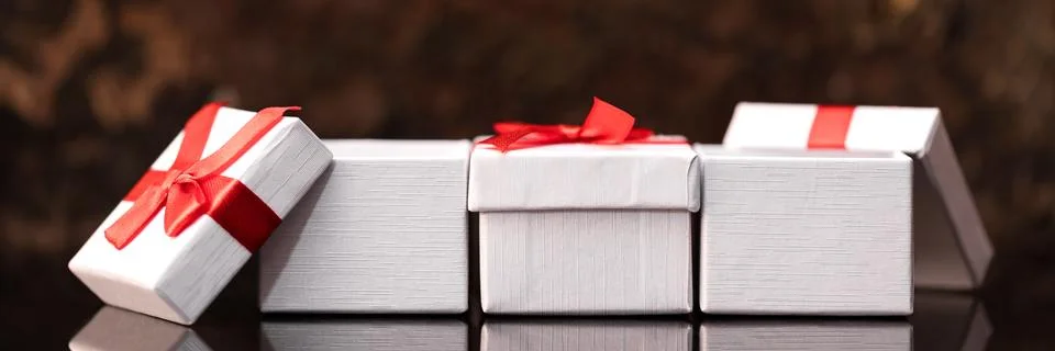Four white gift boxes with red ribbons, panorama 库存照片