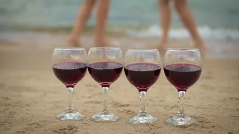 Four wineglasses on sandy ocean beach with dancing happy unrecognizable woman Stock Footage 254089712