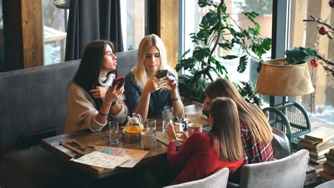 Four woman in cafe using app smartphone playing social network. Technology Stock Footage 86874903