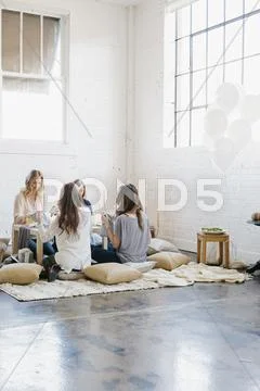 Four women seated at a low table on cushions. Stock Photos