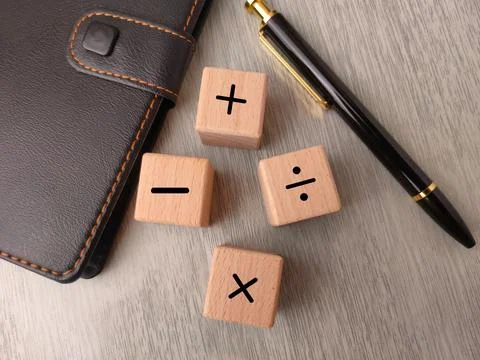 Four wooden blocks featuring basic mathematical symbols, alongside a black .. Stock Photos