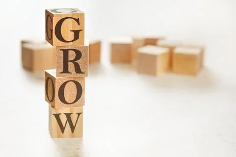 Four wooden cubes arranged in stack with text GROW on them, space for text /  Stockfoto's