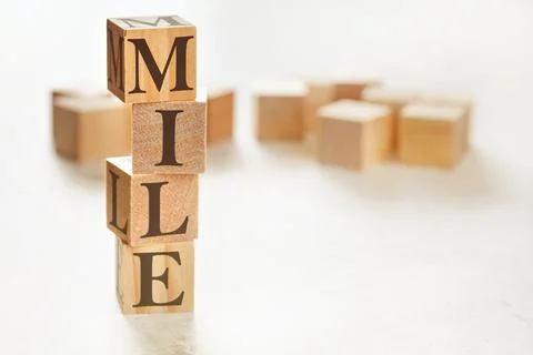 Four wooden cubes arranged in stack with word MILE (meaning Maximum Impact Li Stockfoto's