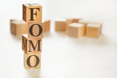 Four wooden cubes arranged in stack with letters FOMO (meaning Fear of Missin Stock Photos
