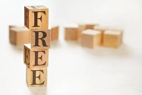 Four wooden cubes arranged in stack with word FREE on them, space for text... Stockfoto's