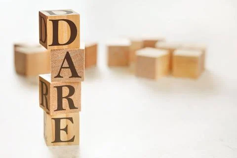 Four wooden cubes arranged in stack with text DARE (meaning Define, Assess... Stockfoto's