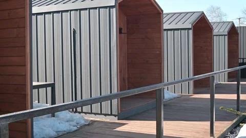 Four wooden structures are visible in a commercial outdoor area with walkways. Stockbeeldmateriaal 337556630