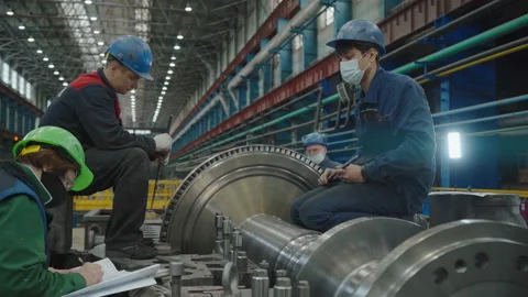 Four workers are discussing work plans regarding a piece of a turbine produced. Stock Footage 152828253