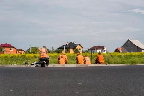 Four workers resting on the road construction site with a houses behind them. Stock Photos