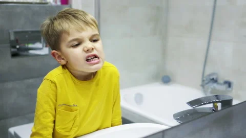 Four-year-old boy examines his teeth in the mirror, making funny faces. Stock Footage 169248356