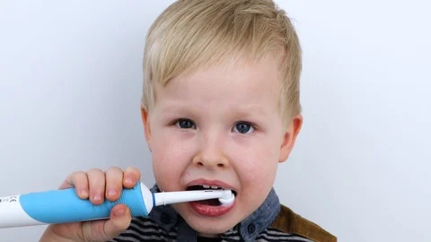 Four year old child brushes his teeth with an electric brush. The boy on a white Stock Footage 124946932