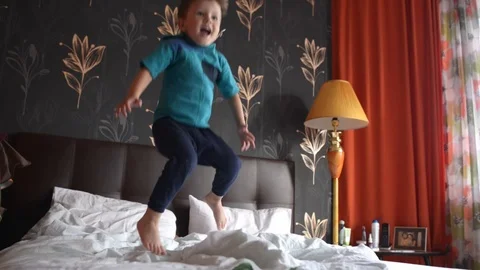 Four years kid jumping on double bed Stock Footage 124400401