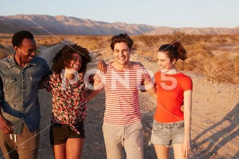 Four young adult friends laughing on a desert road, close up Stock Photos
