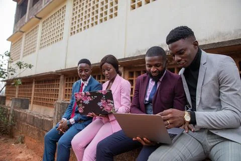 Four young adults work using their laptops and discussing job issues in Afric Stock Photos
