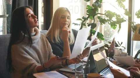 Four young agents sitting in cafe, discussing papers and organizing work Stock Footage 86880970