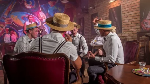 Four young guys are drinking in a pub and they lift their straw hats up Stock Footage 112185273