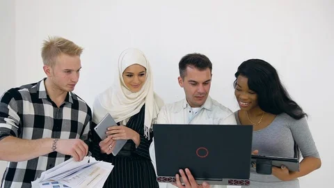 Four young multiracial purposeful office workers using laptop and duscussing Stock Footage 121830670