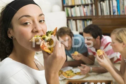 Four young people lying on floor, eating pizza Stock Photos