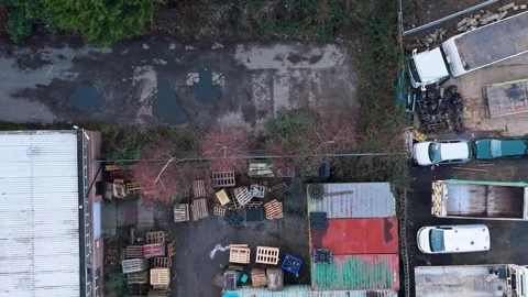 Fox approaches industrial yard as top-down drone reverses over shipping Stock Footage 331461707