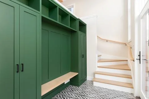 A foyer with a black and white pattern tile floor and green entryway bench. Stock Photos