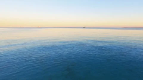 FPV aerial drone flying across a beach and over the blue water of the Vídeo Stock 247300943