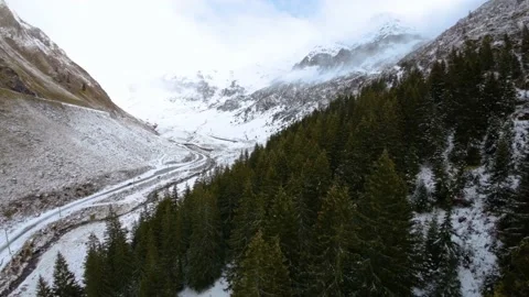 FPV Aerial view of car driving down on a frozen mountain road covered with snow Stock-Footage 224733796