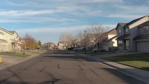 FPV: American flags waving in front of luxury rowhouses in idyllic suburban town Stock Footage