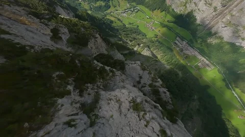 FPV Dive into Shadowed Mountain Valley with Sunlit Alpine Floor Stock Footage 313074171