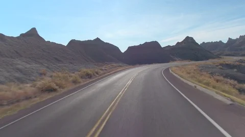 FPV: Driving along the empty road snaking through the Badlands mountain desert Stock Footage 76496147