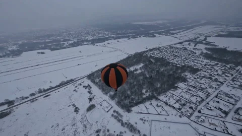 FPV Drone Aerial View of Hot Air Balloon Above Cold White Snow Capped Stock Footage 195977236