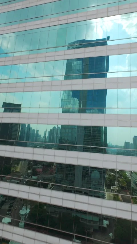 FPV Drone Ascending Along Glass Skyscraper with Jakarta Skyline Reflection Stock Footage 344925539