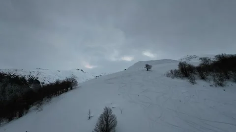 FPV Drone Ascent Over Snowy Hillside with Ski Tracks and Lone Tree Stock Footage 328308236