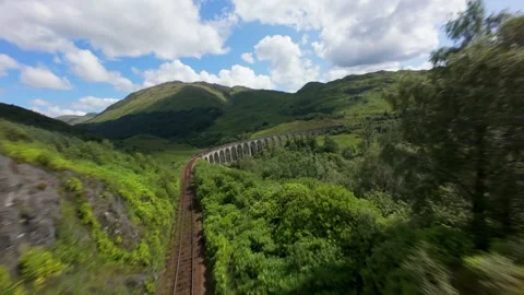 FPV drone banks right over the iconic Glenfinnan Viaduct, then dives to thread Stock Footage 331932681