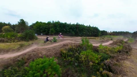 An FPV drone chase in which two motocross racers compete on a forest dirt road Stock Footage 319072425