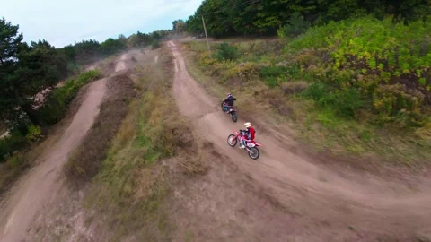 An FPV drone chase in which two motocross racers compete on a forest dirt road Video stock 319072427
