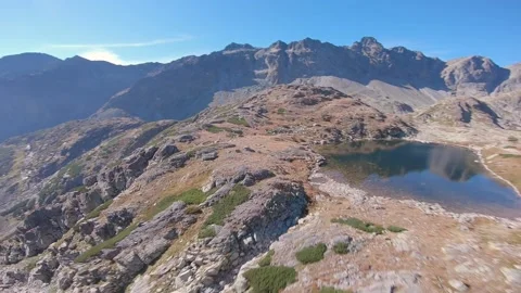 FPV drone cinematic flying close to rocks and lake in high mountains Stock Footage 169280522