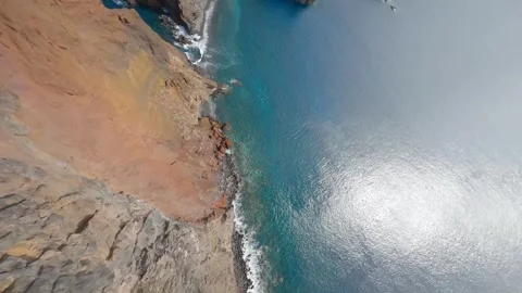 Fpv drone dive along cliff to reach the sea in Madeira Portugal during sunny day Stock Footage 253555546