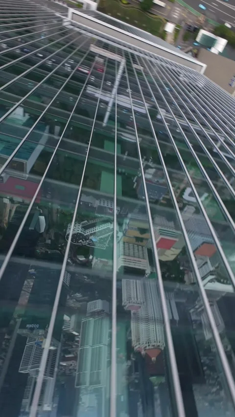 FPV drone dive along glass skyscraper reflecting Jakarta skyline, Indonesia 스톡 동영상 310072007