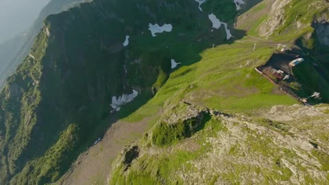 Fpv drone dive down steep alpine cliff in summer mountains Stock Footage 336626101