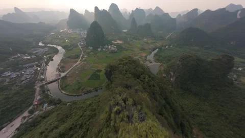 FPV drone dive from karst mountain ridge over Yulong River valley and rice field Stock Footage 348011961