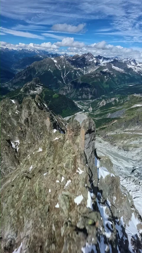 Fpv drone dive rocky snow mountain peak ridge steep alpine valley Stock Footage 340976471