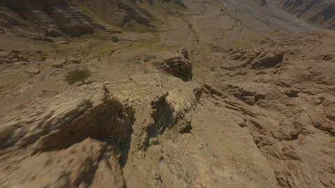 FPV Drone Diving Down Rocky Mountain Face with Rolling Motion in Hatta Desert Stock Footage 321212196