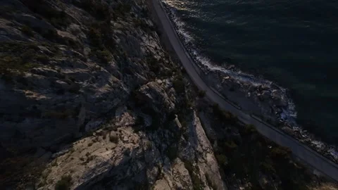 FPV drone diving from high cliff into sea at dramatic sunset Stock Footage 329588034