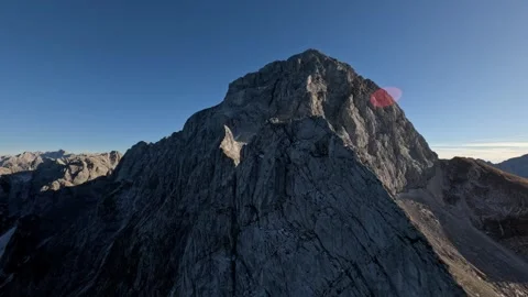 FPV Drone Fast Dive Down Rugged Mountain Peak Patchy Snow, 4K Stock Footage 323462593